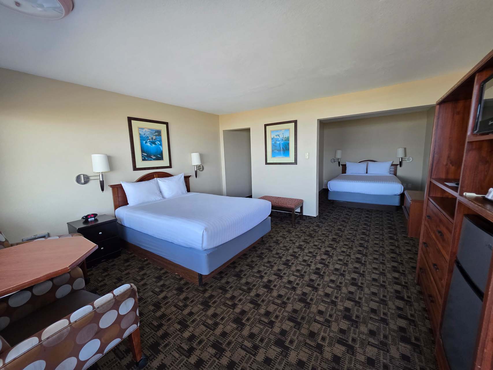 Two Queen room with two beds, a table, an armchair, a TV, and mini-fridge