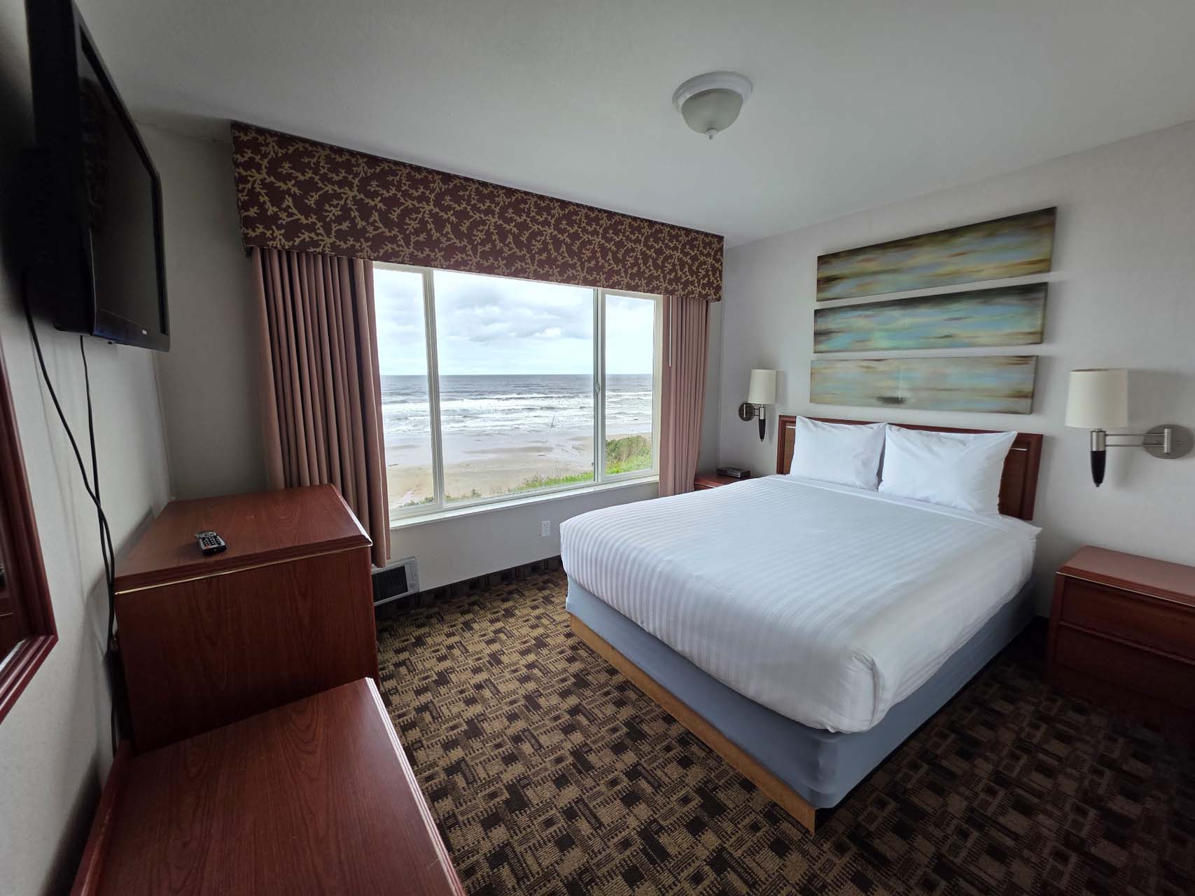 Queen room with a queen bed, a TV, and a large window