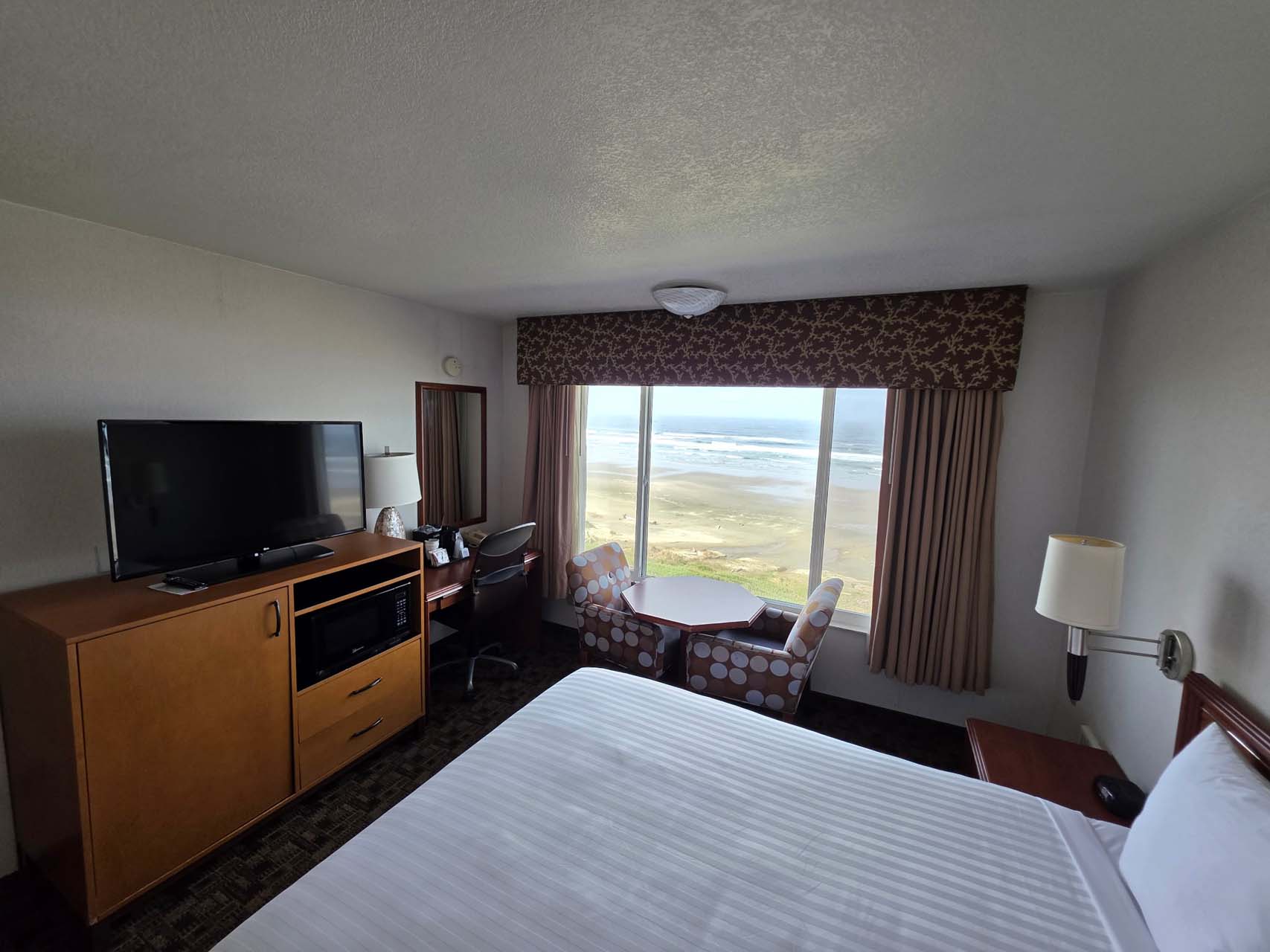 Room with one queen bed, a TV, and a large window